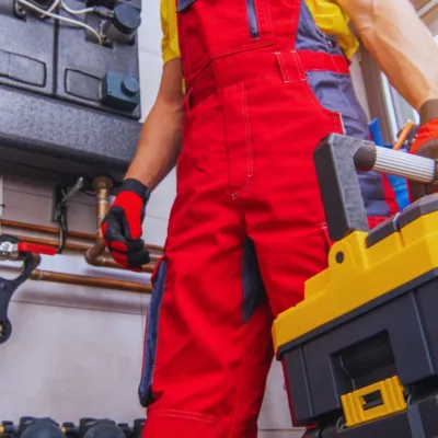 A technician wearing red jumper holding a tool box.