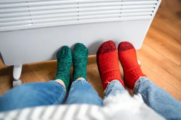 Two pairs of feet can be seen one wearing green color while the other one with the red color. Giving warm and cozy vibes